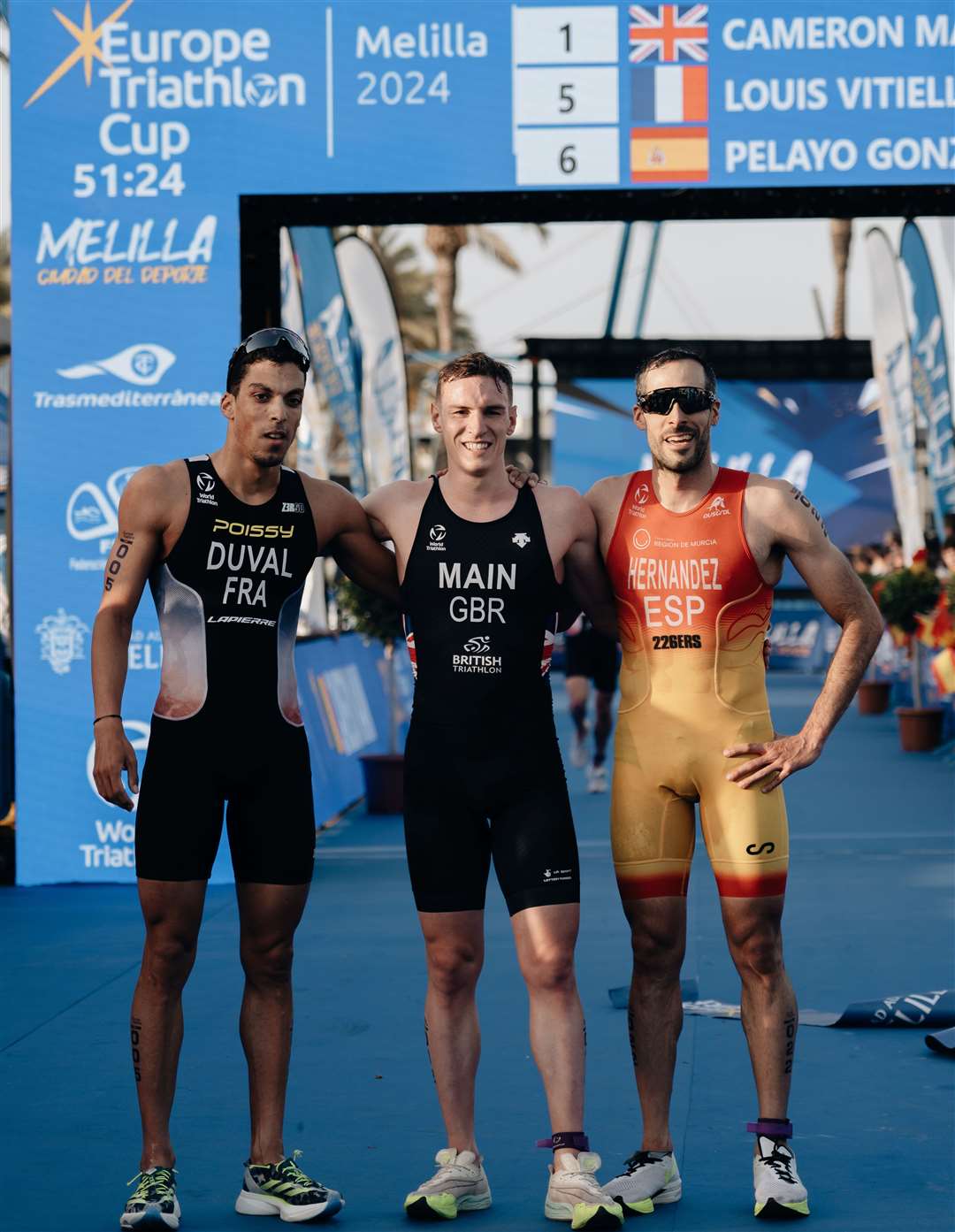 Cameron Main is congratulated by the second and third placed athletes.